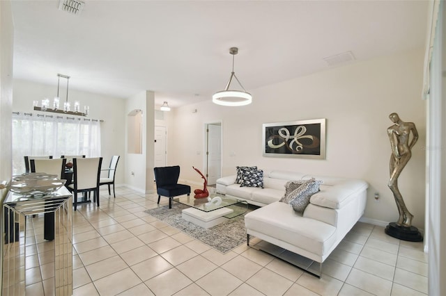 living room with light tile patterned flooring, visible vents, arched walkways, and baseboards