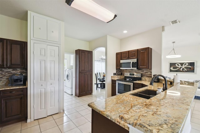 kitchen featuring visible vents, a peninsula, arched walkways, a sink, and stainless steel appliances