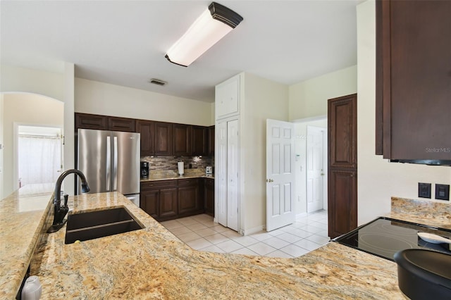 kitchen featuring visible vents, a sink, tasteful backsplash, freestanding refrigerator, and light tile patterned floors