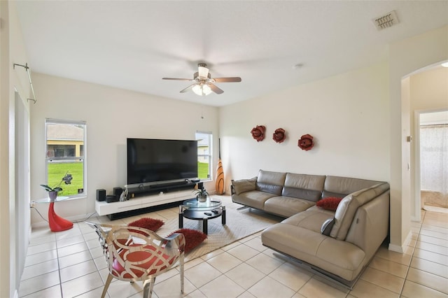 living room with light tile patterned flooring, arched walkways, visible vents, and a wealth of natural light