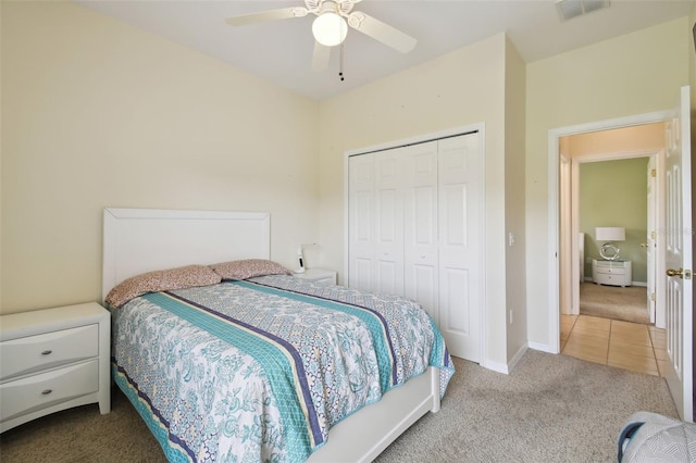 carpeted bedroom featuring visible vents, tile patterned floors, baseboards, ceiling fan, and a closet