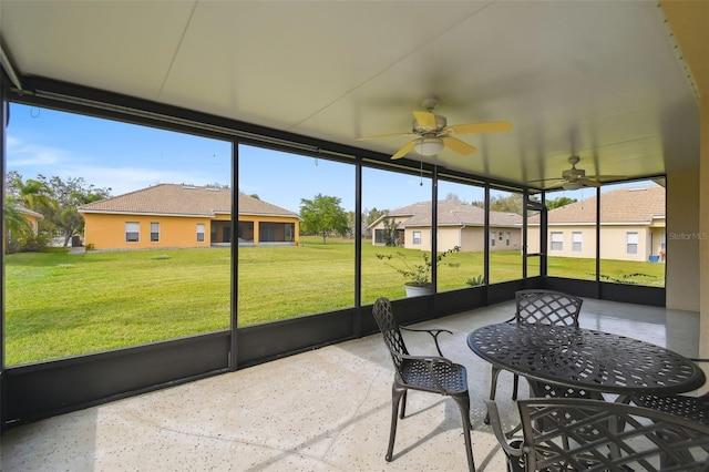 sunroom / solarium with plenty of natural light, a ceiling fan, and a residential view