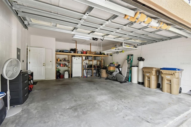 garage with concrete block wall and freestanding refrigerator