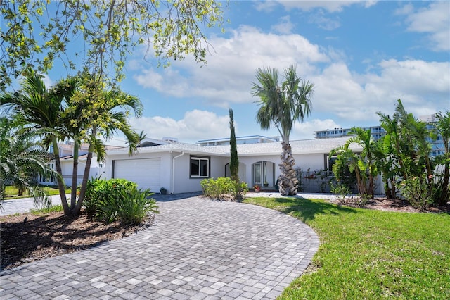 view of front facade with a garage, decorative driveway, a front lawn, and stucco siding