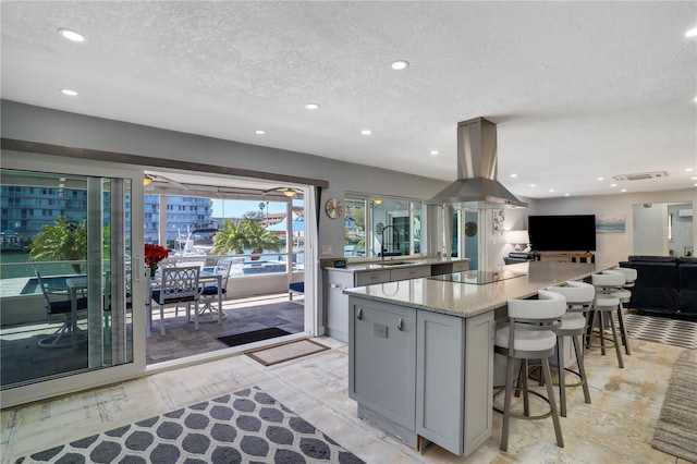 kitchen with a large island, gray cabinets, open floor plan, island range hood, and black electric cooktop