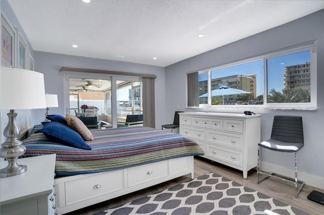 bedroom with wood finished floors, baseboards, recessed lighting, a textured ceiling, and access to outside