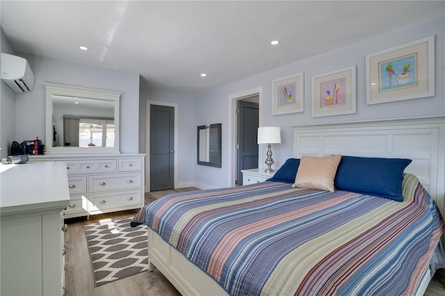 bedroom with recessed lighting, wood finished floors, and a wall mounted air conditioner