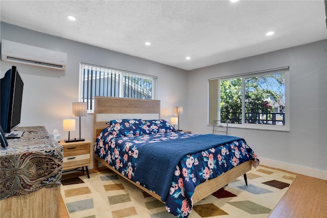 bedroom featuring recessed lighting, a textured ceiling, an AC wall unit, and baseboards