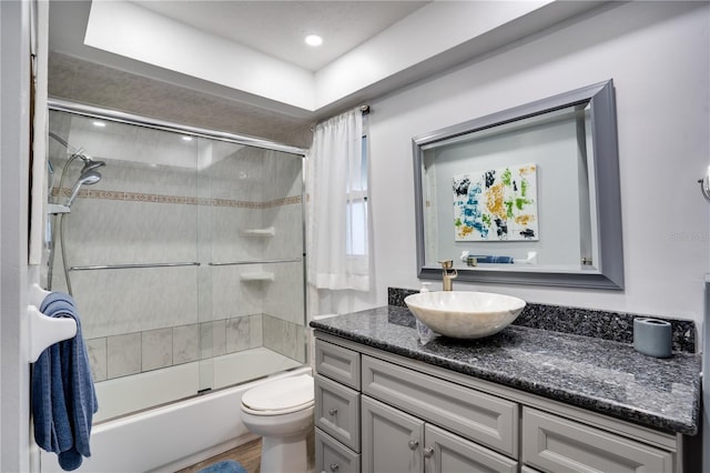 full bath featuring toilet, vanity, and shower / bath combination with glass door