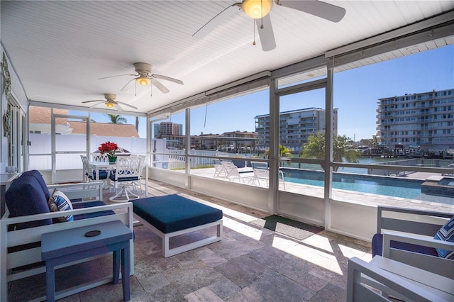 sunroom featuring a city view, a water view, and ceiling fan