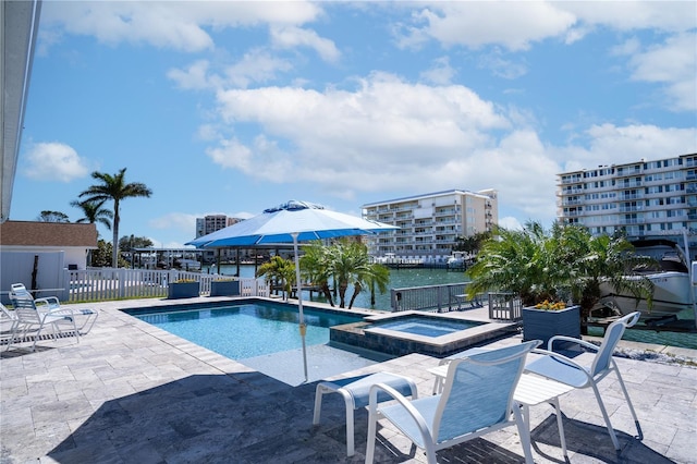 view of swimming pool with a pool with connected hot tub, a water view, a patio, and fence