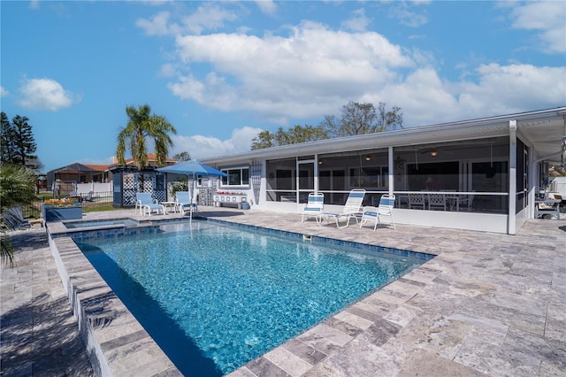 view of pool featuring a patio area, fence, a pool with connected hot tub, and a sunroom