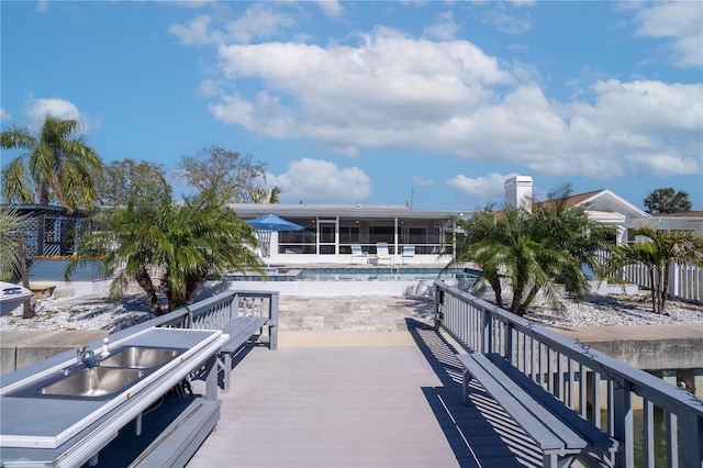 exterior space featuring a community pool, a sunroom, and a wooden deck