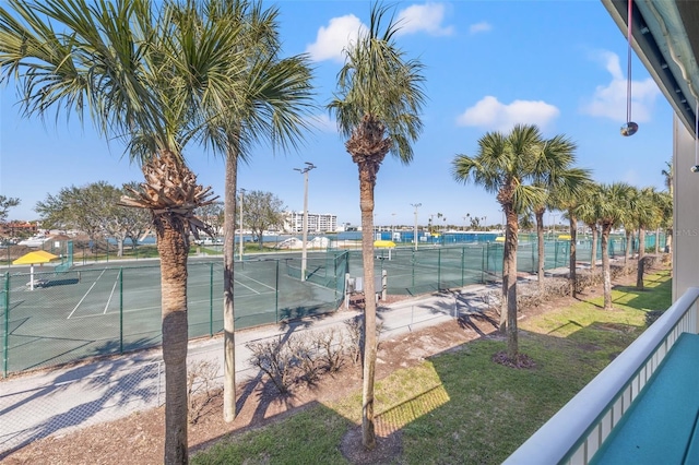 view of tennis court featuring a yard and fence