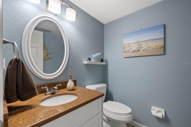 half bathroom featuring visible vents, toilet, vanity, and a textured wall