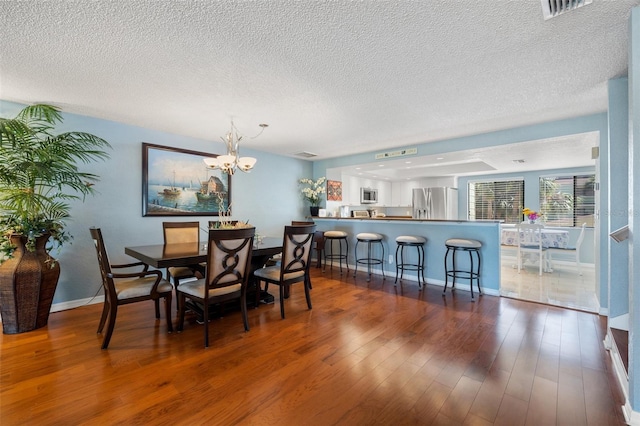 dining room with visible vents, baseboards, a chandelier, wood finished floors, and a textured ceiling