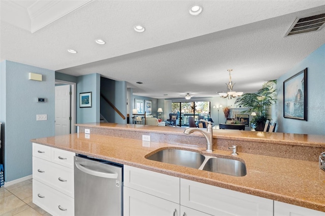 kitchen with light stone countertops, visible vents, a sink, a textured ceiling, and dishwasher