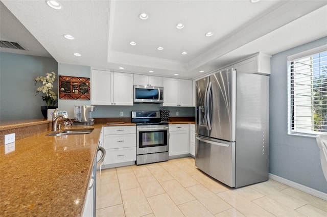 kitchen with visible vents, stainless steel appliances, white cabinetry, a raised ceiling, and a sink