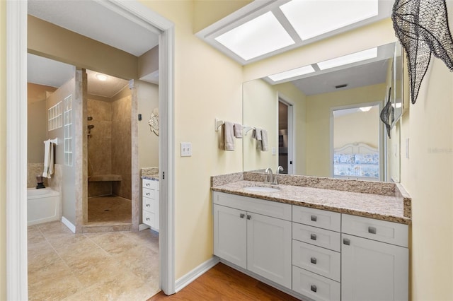 full bath featuring a tile shower, vanity, and baseboards