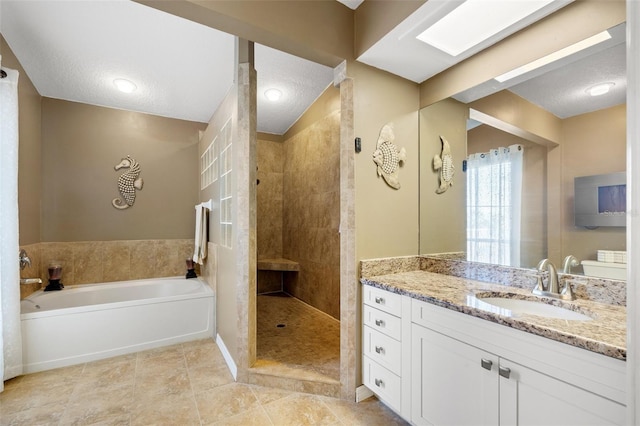 bathroom featuring a textured ceiling, a garden tub, vanity, and a walk in shower