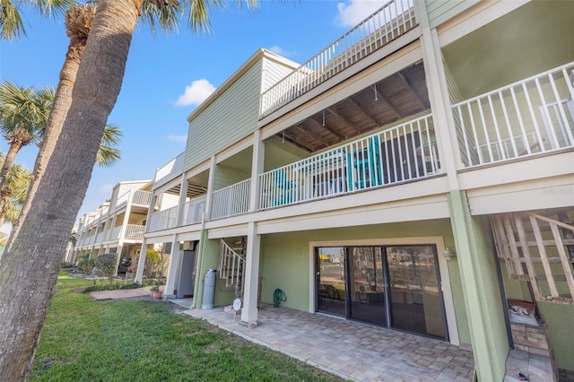 back of property with a patio, a yard, and stucco siding