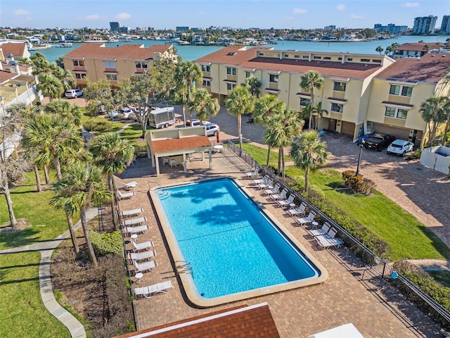 pool with fence, a water view, and a residential view