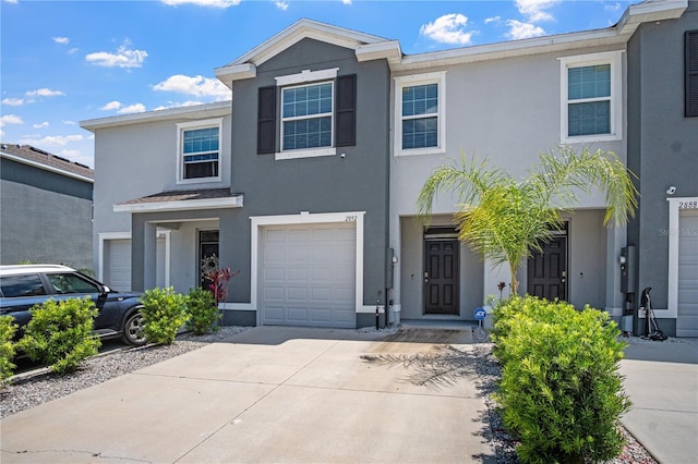 view of front of property featuring an attached garage, concrete driveway, and stucco siding