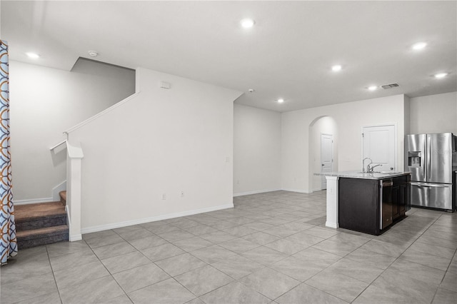 unfurnished living room with arched walkways, a sink, visible vents, recessed lighting, and stairs