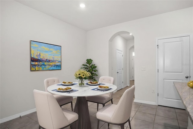 dining room featuring baseboards, arched walkways, recessed lighting, and light tile patterned floors