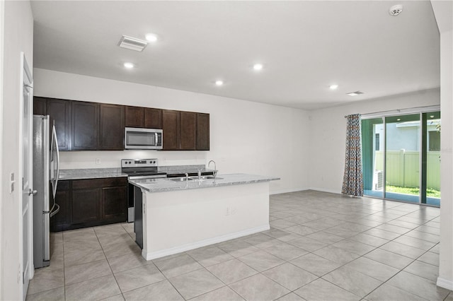 kitchen featuring stainless steel appliances, visible vents, a sink, light tile patterned flooring, and a kitchen island with sink