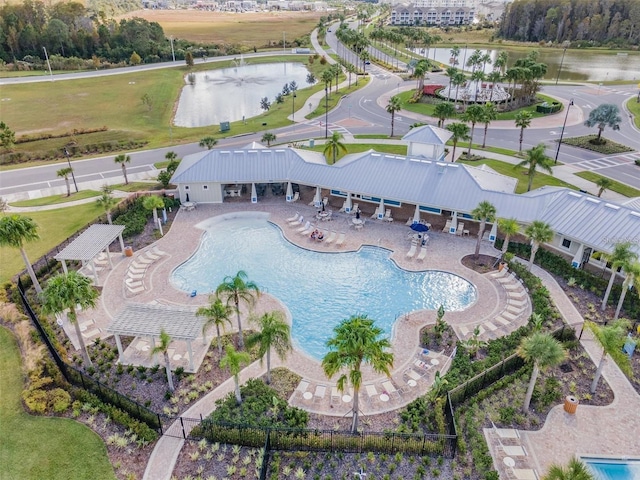 pool featuring a patio, a water view, and fence