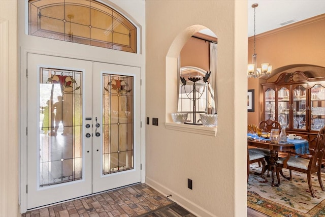 foyer with visible vents, baseboards, an inviting chandelier, brick floor, and french doors