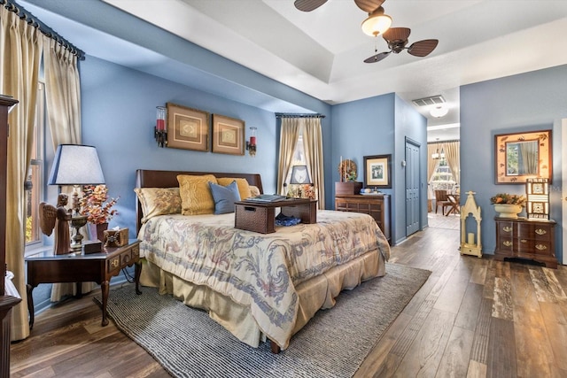 bedroom featuring a tray ceiling, a ceiling fan, visible vents, and wood-type flooring