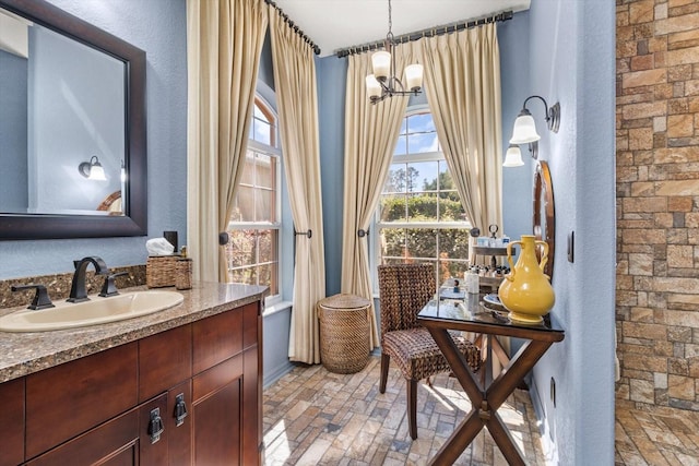 bathroom with brick floor, a notable chandelier, and vanity