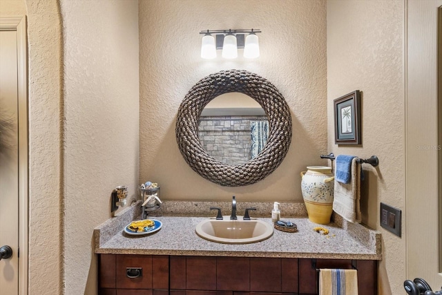 full bathroom featuring vanity and a textured wall