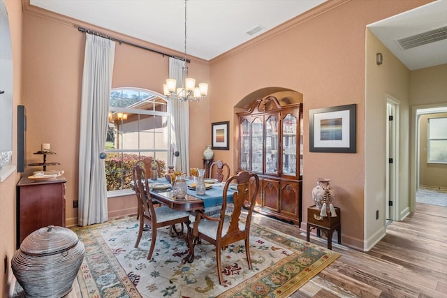 dining room with ornamental molding, wood finished floors, visible vents, and a chandelier