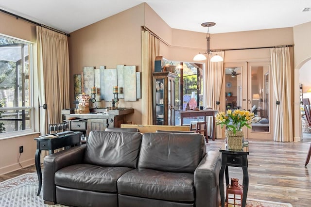 living area featuring visible vents, arched walkways, baseboards, and wood finished floors