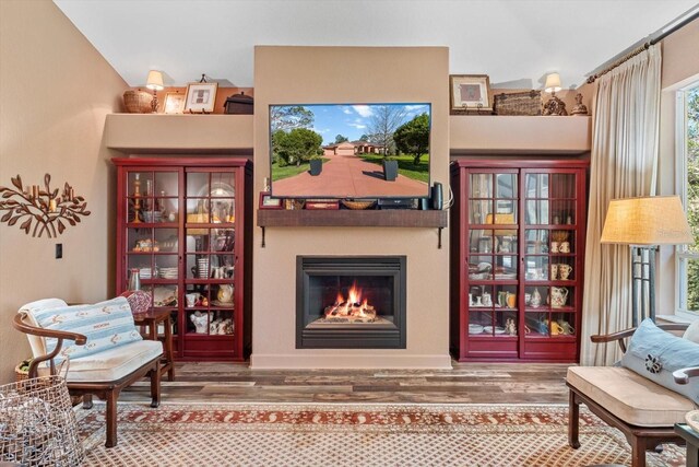 living area featuring wood finished floors and a warm lit fireplace