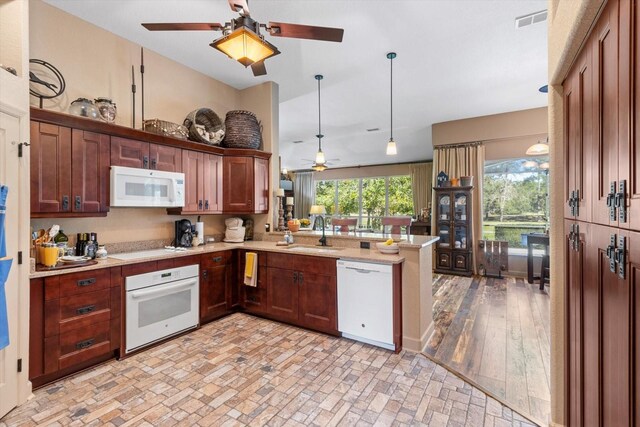 kitchen featuring visible vents, light countertops, a peninsula, white appliances, and a sink