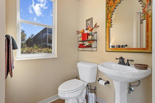 half bath with toilet, baseboards, and a sink