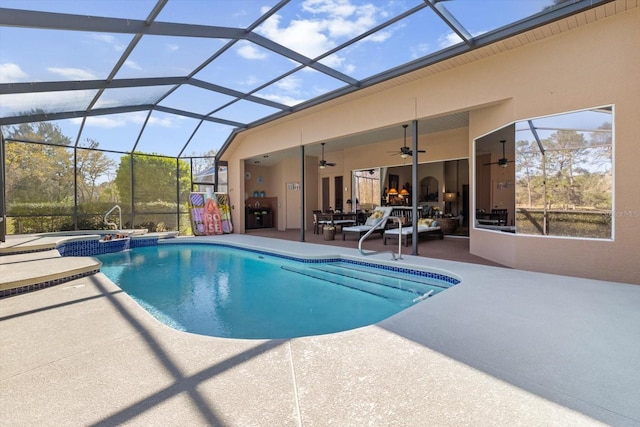 view of swimming pool with glass enclosure, a pool with connected hot tub, a ceiling fan, and a patio area