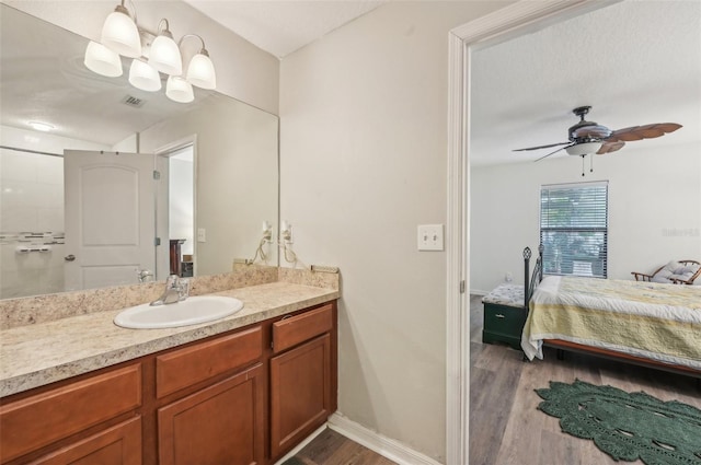 bathroom with visible vents, baseboards, wood finished floors, vanity, and a ceiling fan