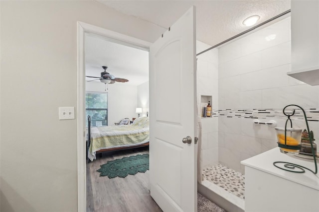 ensuite bathroom featuring a textured ceiling, wood finished floors, connected bathroom, tiled shower, and ceiling fan