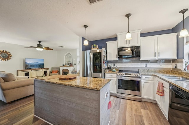 kitchen with light wood-type flooring, a sink, black appliances, white cabinets, and open floor plan