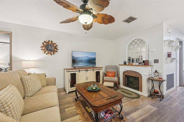 living area with visible vents, light wood-style floors, ceiling fan, and a fireplace