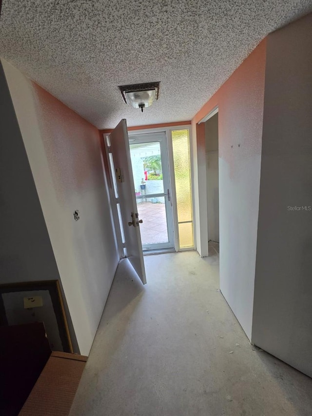 corridor with a textured ceiling and concrete floors