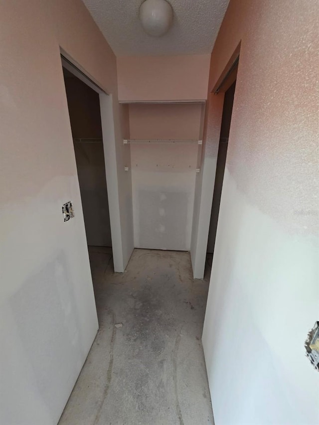 corridor with a textured ceiling and concrete flooring