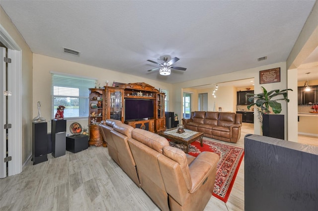 living area featuring light wood finished floors, visible vents, and a textured ceiling