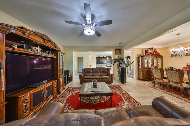 living room with ornamental molding, light wood-style flooring, ceiling fan with notable chandelier, a textured ceiling, and stairs