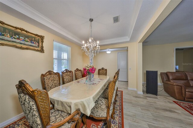 dining area featuring visible vents, crown molding, baseboards, a tray ceiling, and light wood-style floors